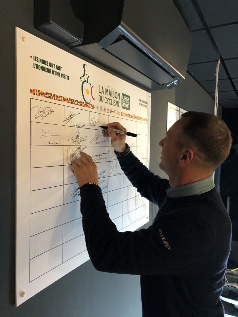 Tableau des signatures - Francis Mourey signe le tableau à la Maison du Cyclisme Liège Bastogne Liège